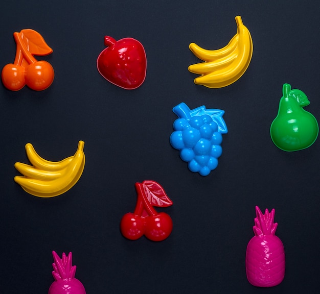 La plastica multicolore gioca i frutti su un fondo nero