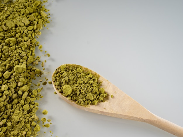 La polvere di tè Matcha di colore verde è sparsa su uno sfondo bianco. Copia spazio.