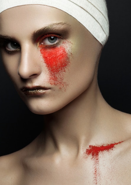 La polvere rossa della chirurgia plastica della fasciatura della donna di bellezza compone sulla parete nera