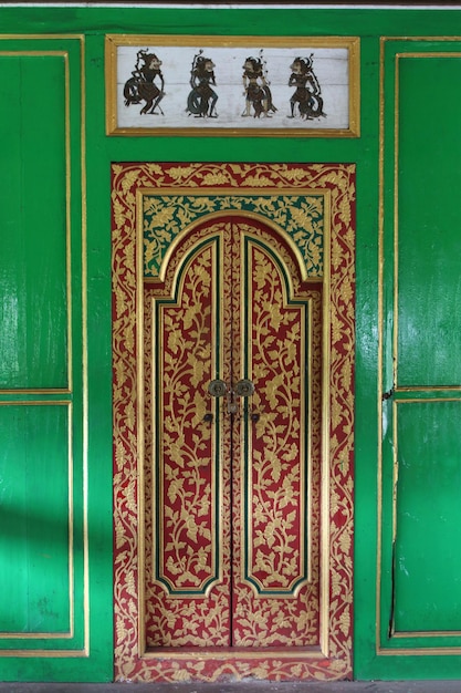 La porta di legno di scultura balinese sulla parete verde