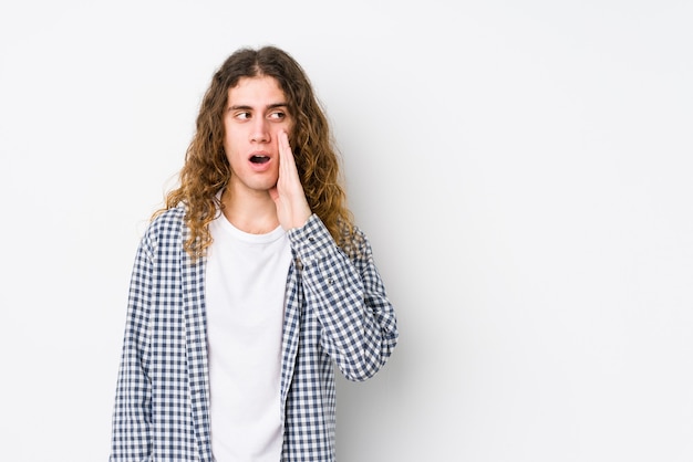 La posa isolata del giovane uomo dei capelli lunghi sta dicendo una notizia segreta di frenata calda e sta guardando da parte