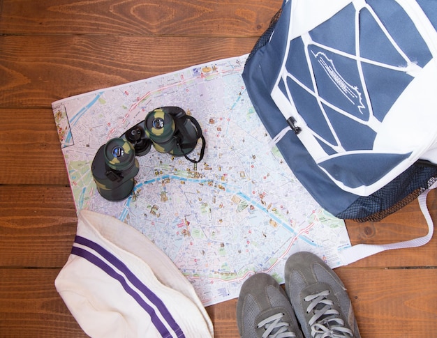 La preparazione per il viaggio viaggio zaino binocolo fotocamera mappa su sfondo di legno