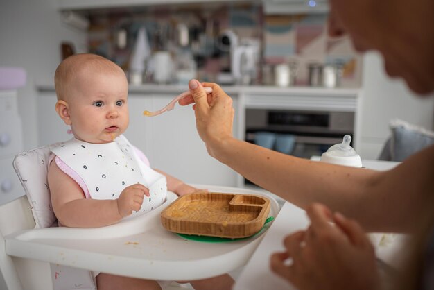 la prima mamma che allatta il bambino nutre un bambino sorpreso con un cucchiaio