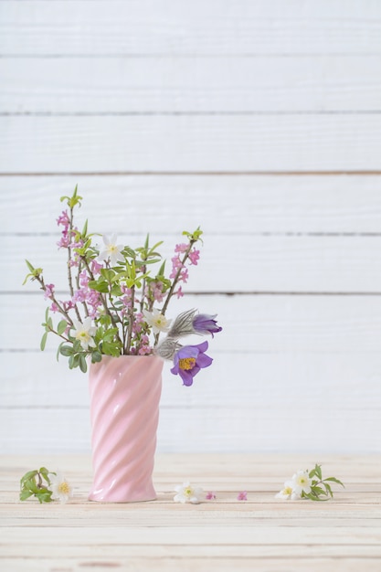 La primavera fiorisce in vaso su fondo di legno bianco