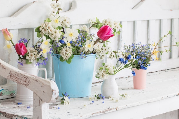 La primavera fiorisce nell'interno bianco d'annata con il vecchio banco di legno