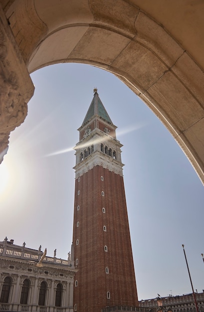 La punta e la parte centrale del campanile della Basilica di San Marco a Venezia vista da sotto uno dei portici di piazza san marco dove si trova il campanile stesso. Tiro verticale.