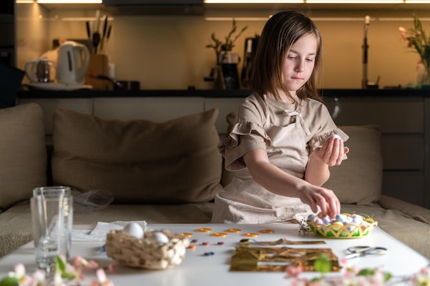 La ragazza a casa in cucina tinge le uova per Pasqua