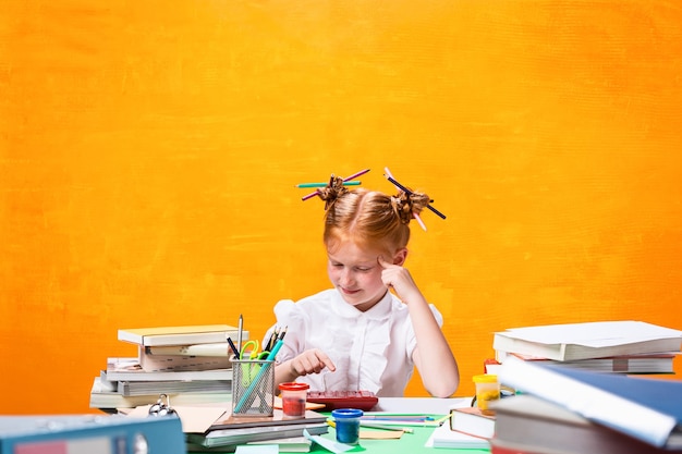 La ragazza adolescente dai capelli rossi con molti libri a casa. Foto in studio
