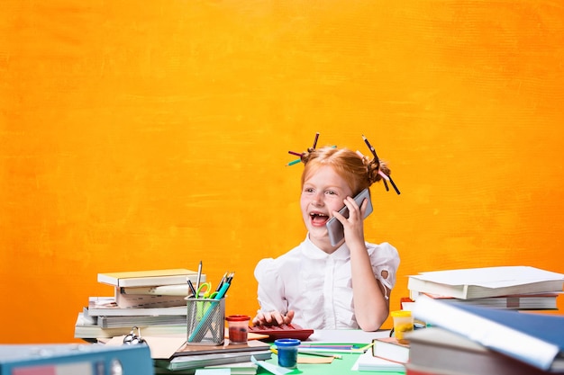 La ragazza adolescente dai capelli rossi con molti libri a casa. Foto in studio