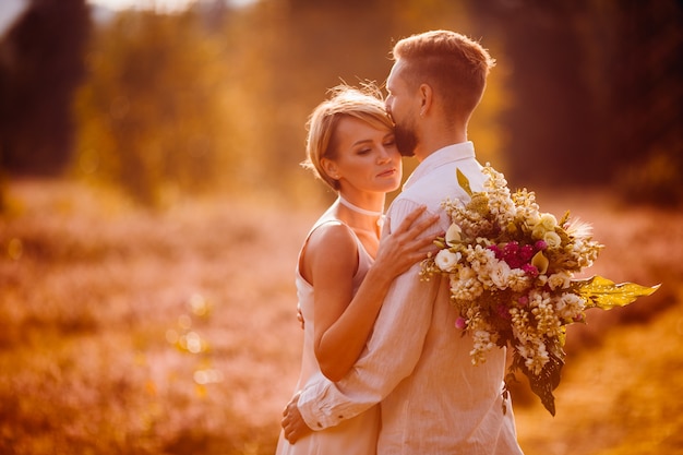 La ragazza affascinante mantiene un bouquet e abbraccia il suo ragazzo