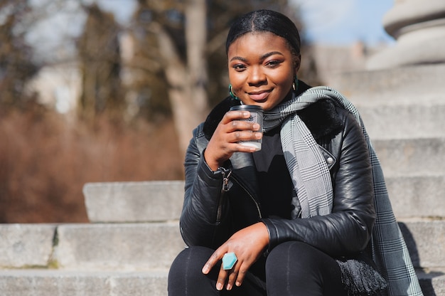 La ragazza afroamericana cammina attraverso il posto con il caffè