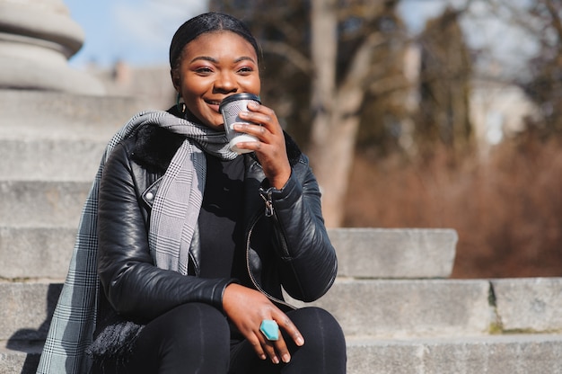 La ragazza afroamericana cammina attraverso il posto con il caffè