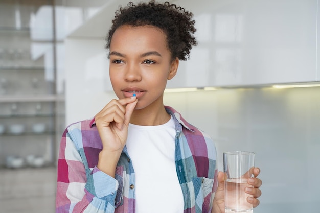 La ragazza afroamericana sta assumendo farmaci per la prevenzione delle malattie pillole contraccettive