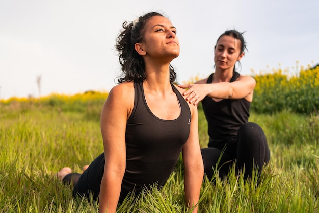 La ragazza aiuta un amico a eseguire una posa yoga nella natura