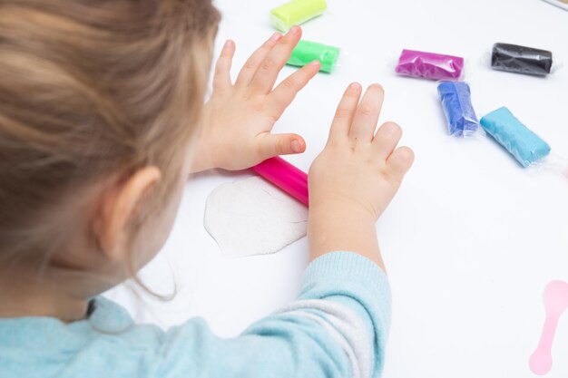 La ragazza al tavolo sta giocando con la pasta da modellare. Giochi per bambini per la motricità fine