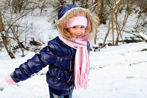 La ragazza all'aperto sta giocando con la neve all'aperto