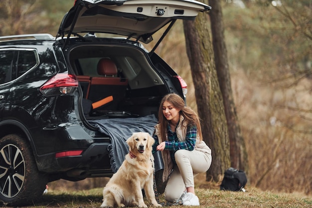 La ragazza allegra ha camminato con il suo cane all'aperto nella foresta nella stagione autunnale o primaverile