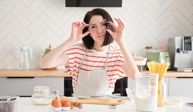 La ragazza allegra in cucina prepara i biscotti di Natale