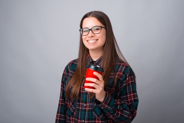 La ragazza allegra sta sorridendo mentre teneva porta via la tazza su bianco