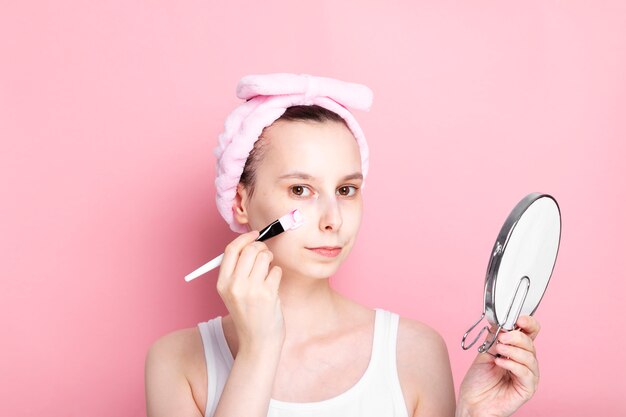 La ragazza applica la maschera cosmetica con la spazzola