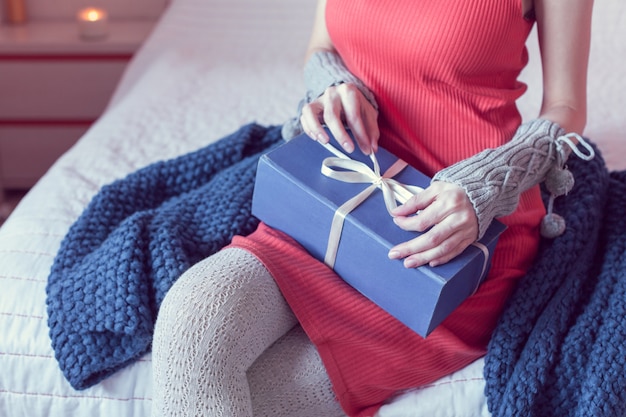 La ragazza apre un regalo mentre è seduta sul letto