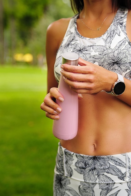 La ragazza apre una bottiglia d'acqua dopo l'allenamento sportivo