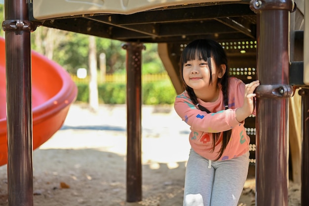 La ragazza asiatica carina ama giocare nel parco giochi all'aperto nel fine settimana o nel cortile della scuola