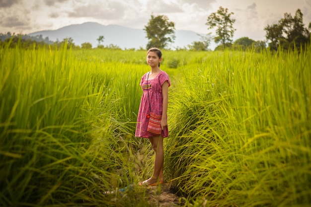 La ragazza asiatica felice gode di nel giacimento verde del riso, campagna della Tailandia al tramonto