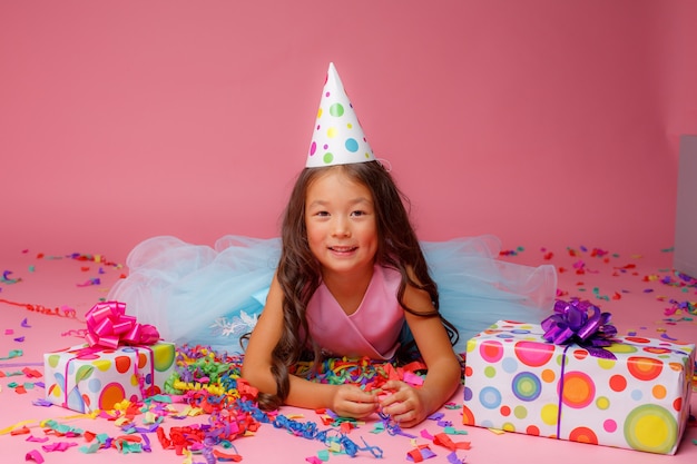 La ragazza asiatica festeggia il compleanno, coriandoli sul rosa