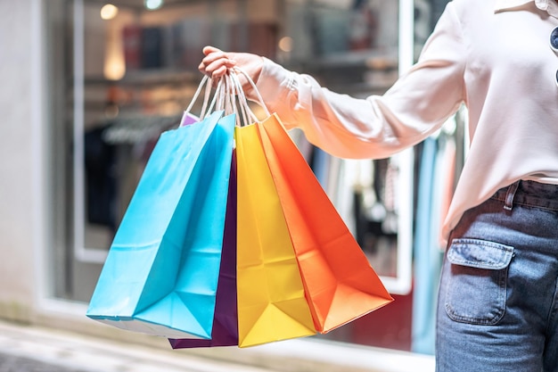 La ragazza asiatica ha eccitato la bella ragazza con la carta di credito della tenuta e le borse della spesa che si divertono nello shopping espressione rilassata, concetto di stile di vita.