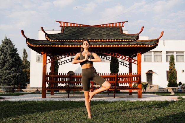 La ragazza asiatica in forma medita sullo sfondo di un gazebo cinese Rilassamento e meditazione all'aperto