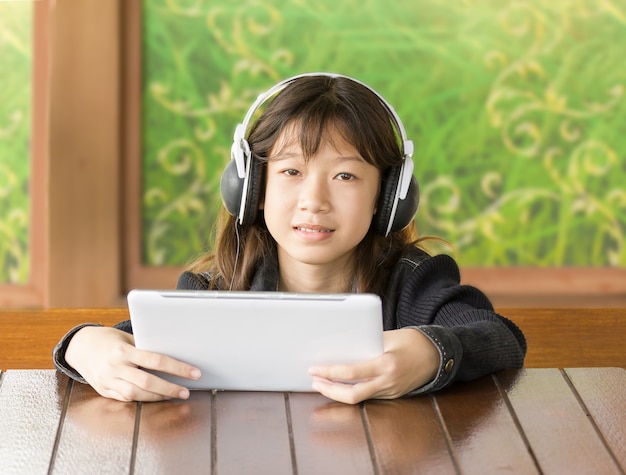 La ragazza asiatica sta ascoltando musica tramite le cuffie