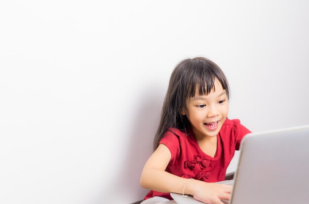 La ragazza asiatica sta godendo qualcosa sul suo computer