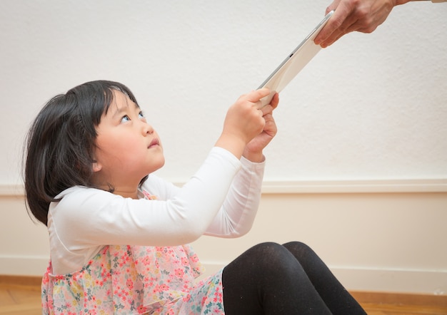 La ragazza asiatica sta strappando un tablet dalla mano di un genitore.