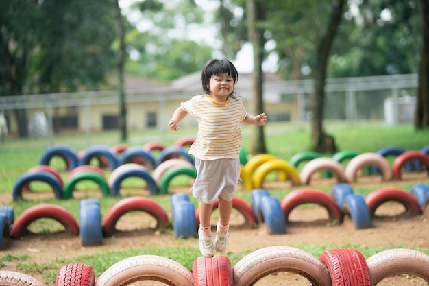 La ragazza asiatica sveglia sorride e gioca a scuola o nel cortile dell'asilo o nel parco giochi Attività estiva sana per i bambini Piccola ragazza asiatica che si arrampica all'aperto nel parco giochi Bambino che gioca nel parco giochi all'aperto