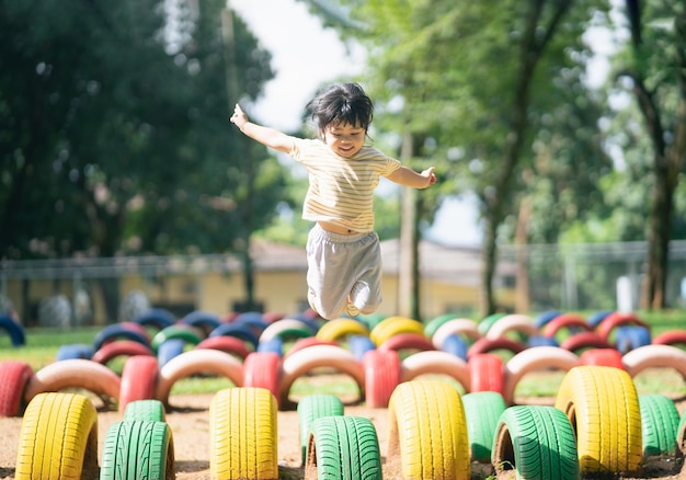 La ragazza asiatica sveglia sorride e gioca a scuola o nel cortile dell'asilo o nel parco giochi Attività estiva sana per i bambini Piccola ragazza asiatica che si arrampica all'aperto nel parco giochi Bambino che gioca nel parco giochi all'aperto