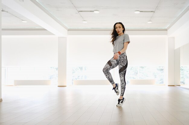 La ragazza atletica che esegue gli sport e balla da solo in uno studio