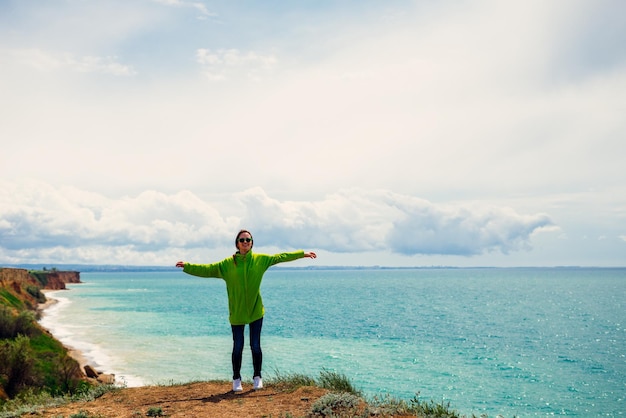 La ragazza attiva in una felpa verde viaggia, contro il mare