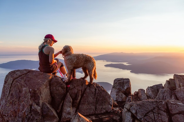 La ragazza avventurosa sta facendo un'escursione con un cane in cima alla montagna Canada BC