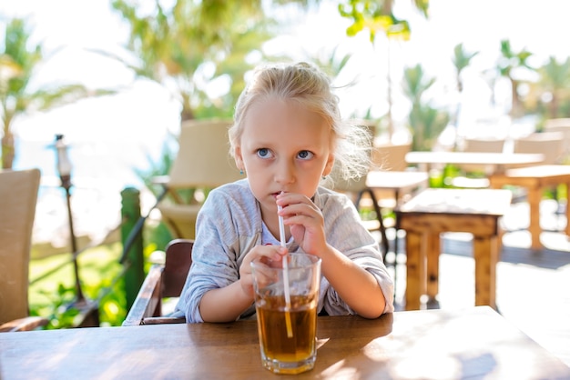 La ragazza beve cocktail di frutta contro il mare