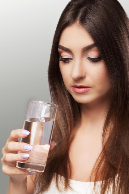 La ragazza beve l'acqua Aspetto sano del viso Ritratto di una ragazza Il concetto di bellezza e salute