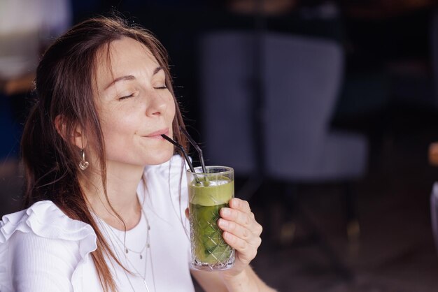 La ragazza beve un cocktail fresco e sano nella caffetteria moderna