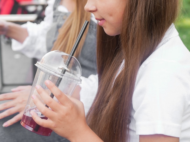 La ragazza beve un drink e guarda il telefono. divertiti