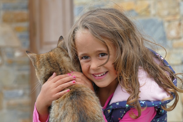 La ragazza bionda di 4 anni abbraccia un gattino