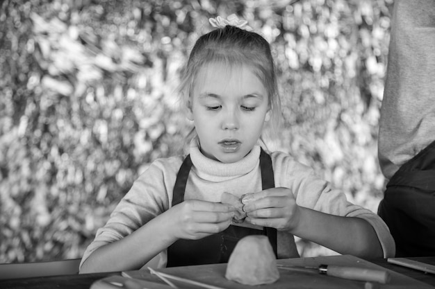 La ragazza bionda scolpisce da argilla in studio. Classe di arte