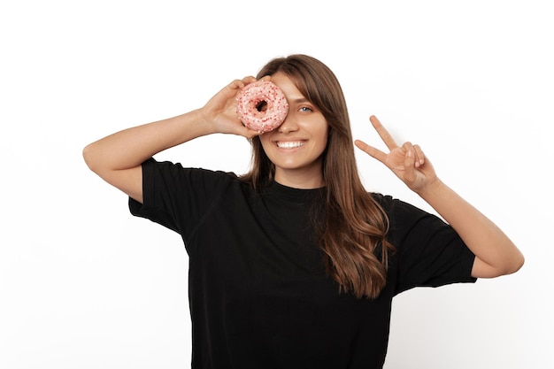 La ragazza bionda si diverte mentre tiene una ciambella davanti a un occhio