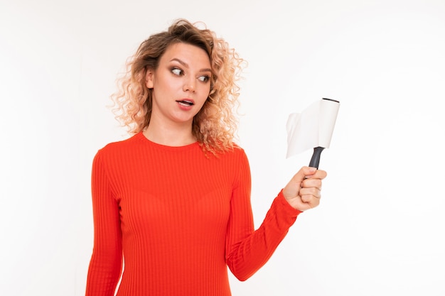 La ragazza bionda sorpresa sta pulendo i suoi vestiti dalla lana su bianco