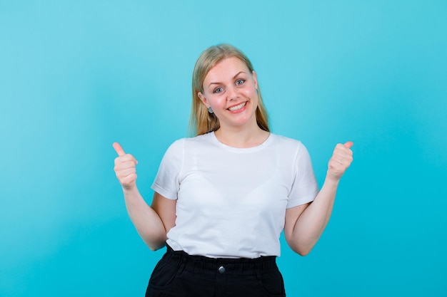 La ragazza bionda sorridente sta mostrando gesti perfetti su sfondo blu