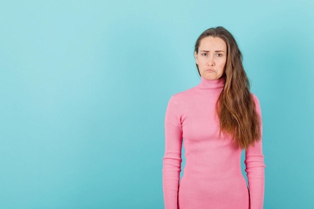 La ragazza bionda sta mostrando il mimetismo del viso triste su sfondo blu