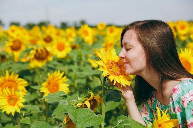 La ragazza bruna che annusa un girasole nel campo